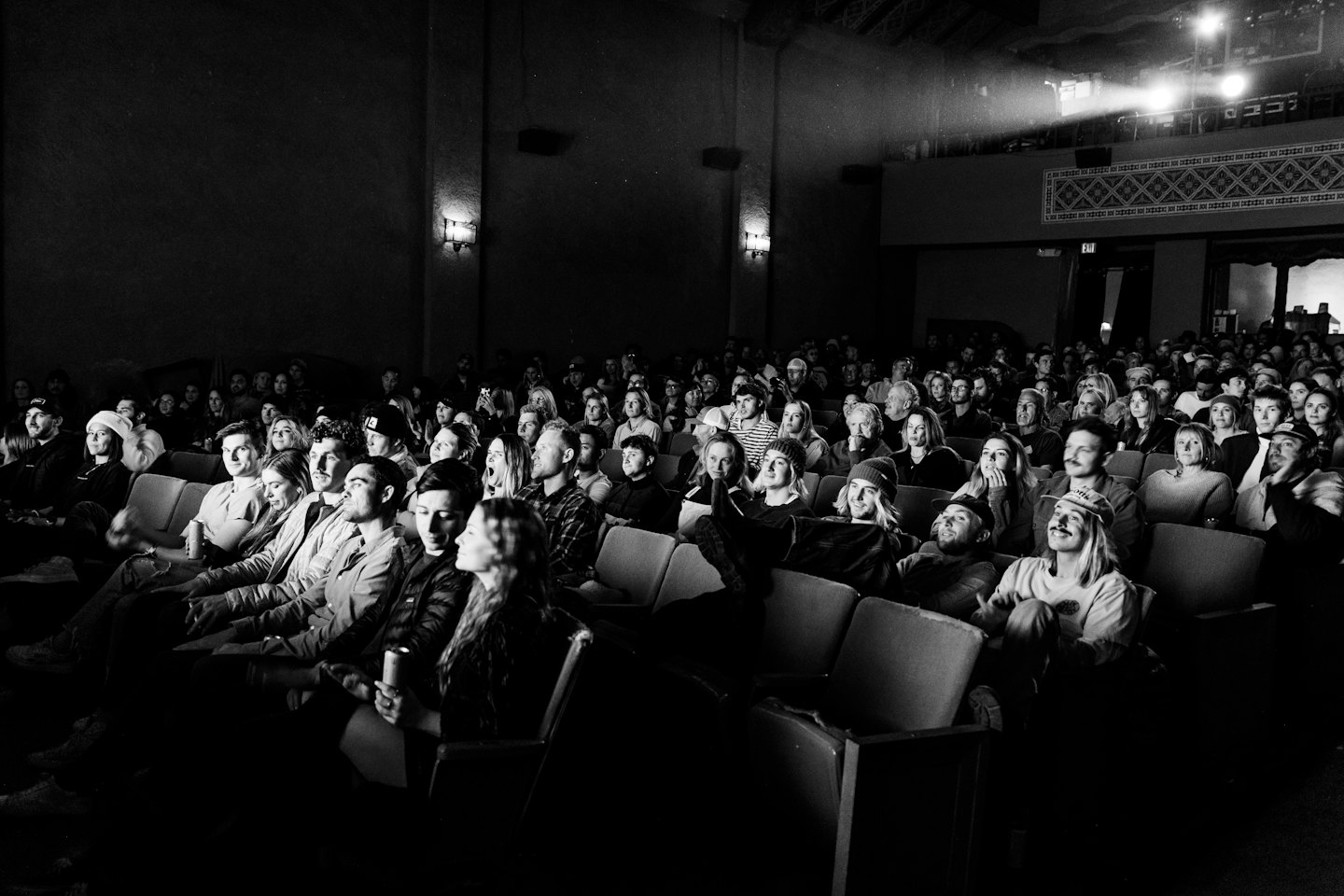 Un pubblico assiste a uno spettacolo in un'aula teatrale buia.