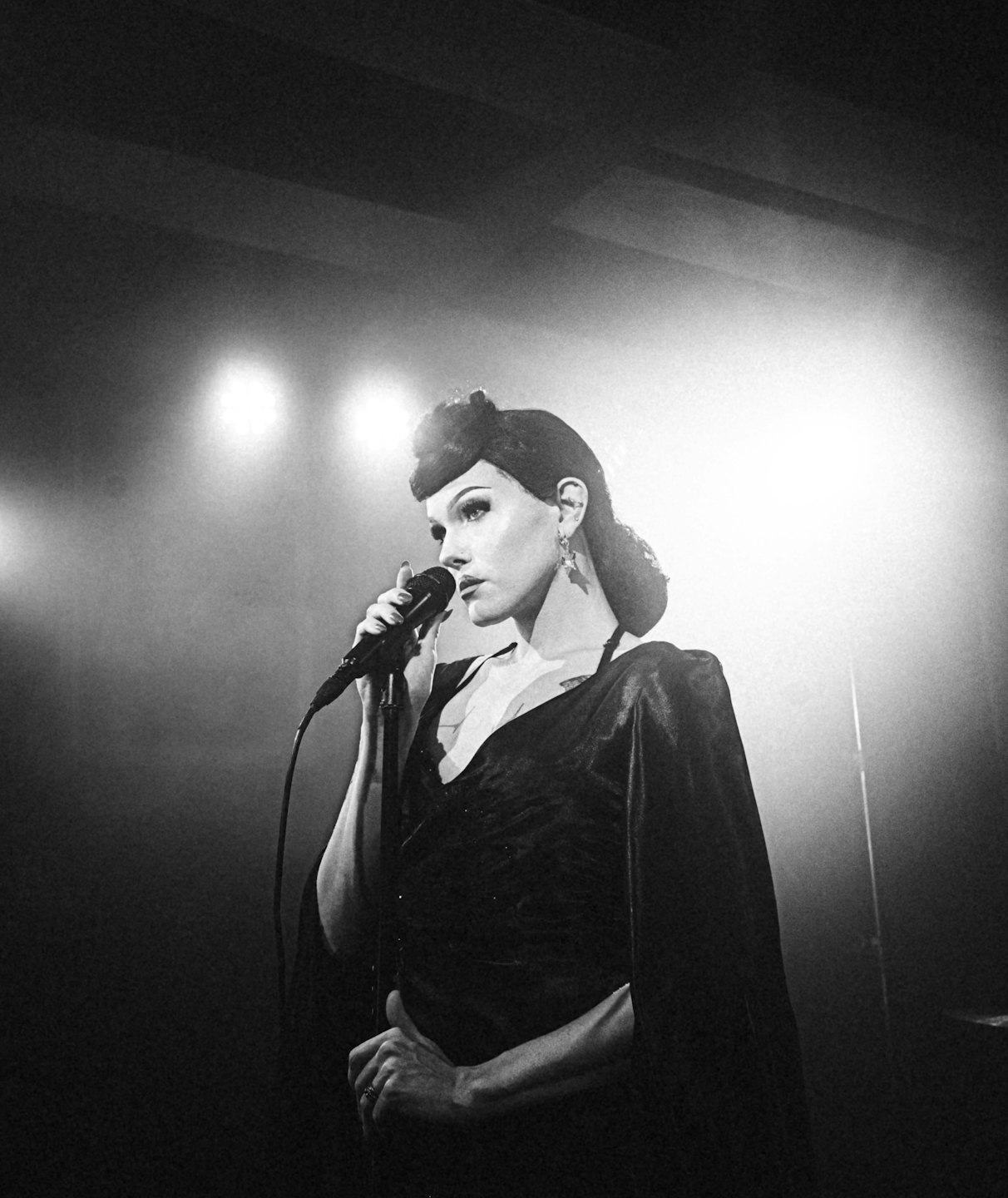 Donna con un elegante abito scuro canta al microfono.